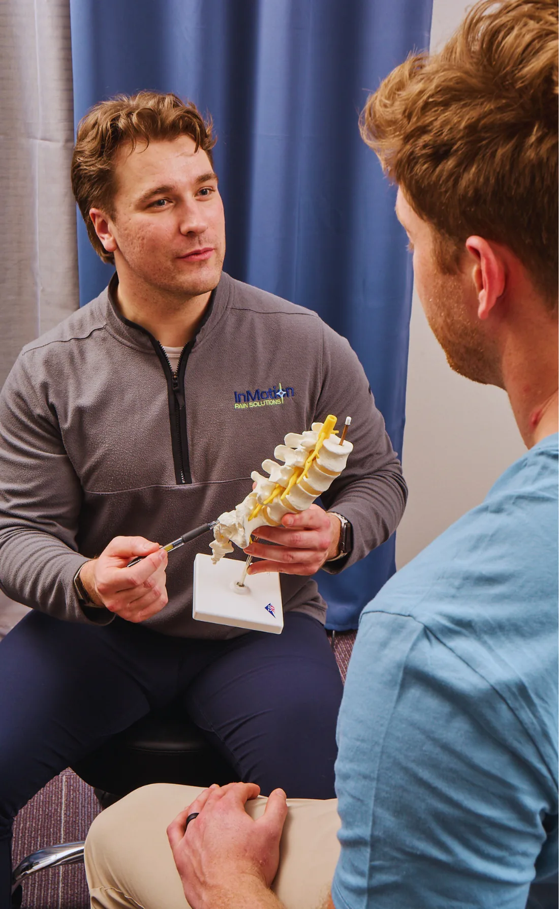 Dr. Haden Hammel using a spine model to explain the source of a patient's pain